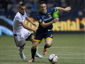 Los Angeles Galaxy's Robbie Keane, right, of Ireland, tries to get away from Vancouver Whitecaps' Russell Teibert during the second half of an MLS soccer game in Vancouver, B.C., on Saturday April 4, 2015.