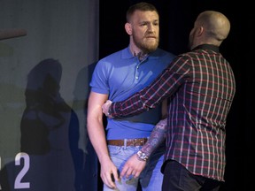 Conor McGregor is held back from an altercation with opponent Nate Diaz during the UFC 202 news conference.