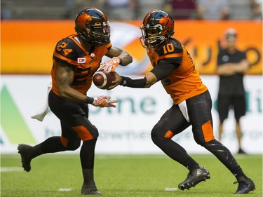 BC Lions #10 Jonathon Jenning hands off to #24 Jeremiah Johnson during play against the Hamilton Tiger-Cats.