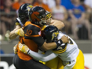 BC Lions #10 Jonathon Jenning is wrapped up by Hamilton Tiger-Cats  #7 John Chick and #21 Simoni Lawrence.