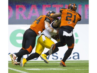 BC Lions #44 Adam Bighill and #21 Ryan Phillips tackle Hamilton Tiger-cats #2 Chad Owens.