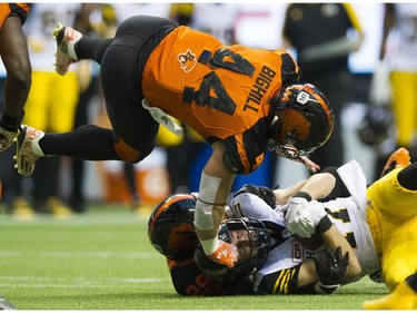 BC Lions #44  Adam Bighill dives over Lions #29 Steven Clarke as he tackles Hamilton Tiger-Cats #17 Luke Tasker.