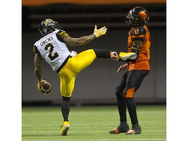 Hamilton Tiger-Cats  #2 Chad Owens  gestures to BC Lions #0 Loucheiz Purifoy as he holds Owen's foot after he completed a pass.