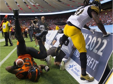 Hamilton Tiger-Cats  #31 Domonique Ellis  jumps over a photographer after forcing BC Lions #85 Shawn Gore out of bounds.