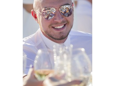 A toast is reflected in the sunglasses of Graeme Lockie at Le Diner en Blanc at Concord Pacific Place Vancouver, August 18 2016.