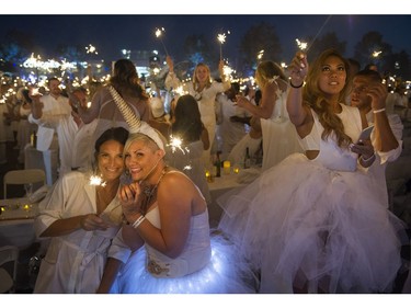 Caitlan Sewell ( L ) and Kimberly Van de Perre ( R ) smile during the sparkler moment at Le Diner en Blanc at Concord Pacific Place Vancouver, August 18 2016.
