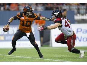 B.C. Lions quarterback Jonathon Jennings is forced to scramble away from rushing defender Alex Singleton of the Calgary Stampeders  during Friday's CFL game at BC Place Stadium in Vancouver. ( Gerry Kahrmann/PNG staff photo)