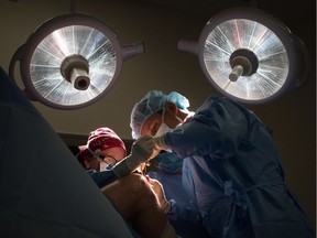 Dr. Anne Wachsmuth, left, assists Dr. Darius Viskontas as they remove a cyst from a male patient's knee, at the Cambie Surgery Centre, in Vancouver on Wednesday, August 31, 2016. Dr. Brian Day, a self-styled champion of privatized health care, is bringing his fight to British Columbia Supreme Court on Tuesday for the start of a months-long trial he says is about patients' access to affordable treatment, while his opponents accuse him of trying to gut the core of Canada's medical system. THE CANADIAN PRESS/Darryl Dyck ORG XMIT: VCRD120
0902 na day
