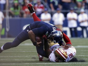 Seattle Seahawks quarterback Russell Wilson, top, is pulled down by San Francisco 49ers' Eli Harold in the second half of an NFL football game, Sunday, Sept. 25, 2016, in Seattle.