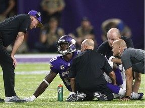FILE - In this Sept. 18, 2016, file photo, Minnesota Vikings running back Adrian Peterson (28) talks with head coach Mike Zimmer, left, after getting injured during the second half of an NFL football game against the Green Bay Packers, in Minneapolis. Peterson hobbled out of the stadium on crutches. Sam Bradford was shaking his left hand in pain for most of the game. The Vikings took their lumps in a 17-14 win over the Packers on Sunday night, largely due to an offensive line that is struggling to protect the team's playmakers.