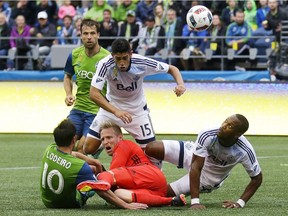 Vancouver Whitecaps goalkeeper David Ousted, lower center, watches the ball with teammates Kendall Waston, right, and Matias Laba (15) after a collision with Seattle Sounders midfielder Nicolas Lodeiro (10) as Sounders' Andreas Ivanschitz, upper left, moves in during the second half of an MLS soccer match, Saturday, Sept. 17, 2016, in Seattle. The Sounders beat the Whitecaps 1-0.
