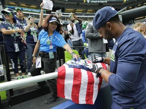 An usher helps Seattle Seahawks wide receiver Doug Baldwin sign an autograph for a fan before an NFL football game against the Miami Dolphins, Sunday, Sept. 11, 2016, in Seattle.