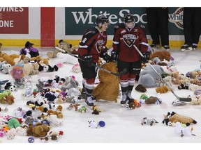 Jack Flaman #18 and Johnny Wesley #39 of the Vancouver Giants help pick up stuffed animals on Teddy Bear Toss night.