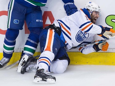 Edmonton Oilers' Patrick Maroon, right, reacts as he falls awkwardly on his left knee after being hit by Vancouver Canucks' James Sheppard during the third period of a pre-season NHL hockey game in Vancouver, B.C., on Wednesday September 28, 2016.