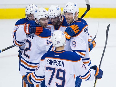 Edmonton Oilers' Jere Sallinen, of Finland, top from left to right, Anton Slepyshev, of Russia, Benoit Pouliot, Griffin Reinhart and Dillon Simpson, bottom, celebrate Reinhart's goal against the Vancouver Canucks during the second period of a pre-season NHL hockey game in Vancouver, B.C., on Wednesday September 28, 2016.