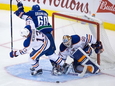 Edmonton Oilers' goalie Jonas Gustavsson, right, of Sweden, stops Vancouver Canucks' Markus Granlund, of Finland, (60) as he's checked by Oilers' Kris Versteeg during the second period of a pre-season NHL hockey game in Vancouver, B.C., on Wednesday September 28, 2016.