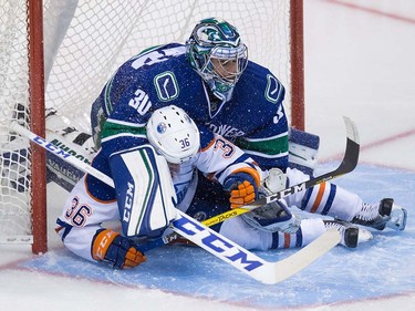 Edmonton Oilers' Drake Caggiula, bottom, slides into Vancouver Canucks' goalie Ryan Miller during the second period of a pre-season NHL hockey game in Vancouver, B.C., on Wednesday September 28, 2016.
