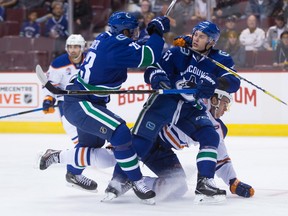 Canucks Alex Edler, left, and Troy Stecher, front right, get twisted up with Edmonton's Connor McDavid on Wednesday.