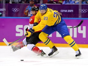 Alexander Edler of Sweden skates against Patrice Bergeron of Canada during the men's hockey gold-medal game at the 2014 Winter Olympics in Sochi, Russia.