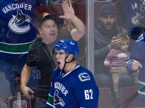 A man covers a child's ears as Vancouver Canucks' Joseph Labate celebrates his goal against the Edmonton Oilers during the second period of a pre-season NHL hockey game in Vancouver, B.C., on Wednesday September 28, 2016.
