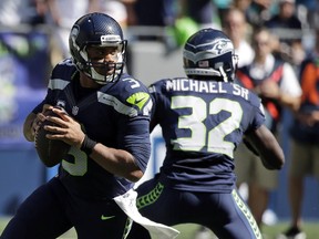 FILE - In this Sunday, Sept. 11, 2016, file photo, Seattle Seahawks quarterback Russell Wilson, left, drops to pass against the Miami Dolphins in the first half of an NFL football game in Seattle. Wilson insists he'll be ready to play against the Los Angeles Rams on Sunday, after suffering a sprained ankle in the third quarter of last week's game against the Dolphins