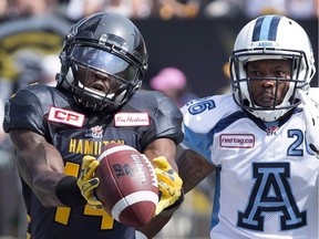 Tiger-Cats wide-receiver Terrell Sinkfield (14) makes a fingertip catch while watched by Toronto Argonauts defensive back Branden Smith (26) at Hamilton in September 2015. The B.C. Lions have now added Sinkfield to their roster after a stint in the NFL.