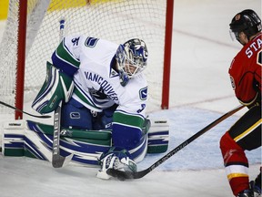 Vancouver Canucks goalie Thatcher Demko, left, grabs the puck away from Calgary Flames' Matt Stajan, during third period pre-season NHL hockey action in Calgary, Friday, Sept. 30, 2016.THE CANADIAN PRESS/Jeff McIntosh ORG XMIT: JMC107