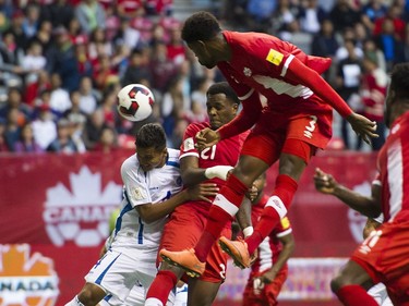El Salvador's Henry Romero defends against Canada's Cyle Larin and Manjreka James.