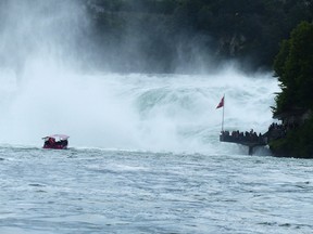 Viewers at the base of the falls, lower right, watch as a small boat edges close to the falls.