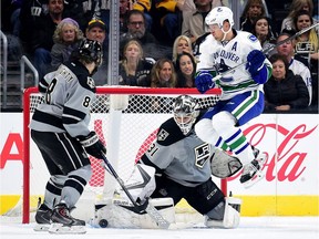 Peter Budaj of the Los Angeles Kings makes a save as Daniel Sedin of the Vancouver Canucks jumps out of the way in front of Drew Doughty during the second period at Staples Center in Los Angeles on Saturday.