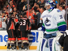 Ryan Miller of the Canucks reacts as Ryan Kesler and Jakob Silfverberg of the Ducks celebrate a first period goal.