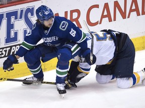 Vancouver Canucks defenseman Philip Larsen (63) falls on top of St. Louis Blues left wing David Perron (57) during second period NHL action in Vancouver, B.C. Tuesday, Oct. 18, 2016.