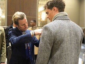 Matthew Millward (pictured at left), the vice president of menswear design at Club Monaco, puts the finishing touches on a model's look during the Fall 2016 Club Monaco collection presentation at New York Fashion Week Collection.
