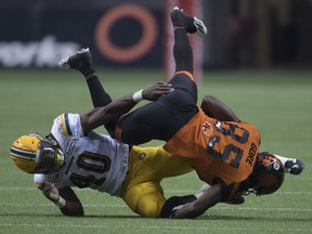 Shawn Gore is flipped over in a tackle by Edmonton Eskimos linebacker Deon Lacey, left, but the B.C. Lions slotback hung on to the ball. The Lions had no turnovers in their 32-25 victory Saturday.