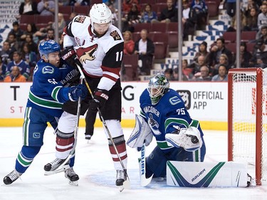 Vancouver Canucks' goalie Jacob Markstrom, right, of Sweden, makes a save as Troy Stecher, left, checks Arizona Coyotes' Martin Hanzal, of the Czech Republic, during the first period of a pre-season NHL hockey game in Vancouver, B.C., on Monday October 3, 2016.
