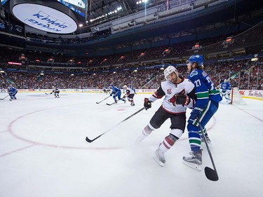 Arizona Coyotes' Jordan Martinook, second right, checks Vancouver Canucks' Ben Hutton during the first period of a pre-season NHL hockey game in Vancouver, B.C., on Monday October 3, 2016.