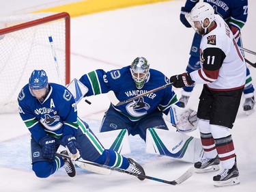 Vancouver Canucks' Alexander Edler, left, of Sweden, deflects the puck wide of the net in front of goalie Jacob Markstrom, of Sweden, as Arizona Coyotes' Martin Hanzal, right, of the Czech Republic, watches during the second period of a pre-season NHL hockey game in Vancouver, B.C., on Monday October 3, 2016.