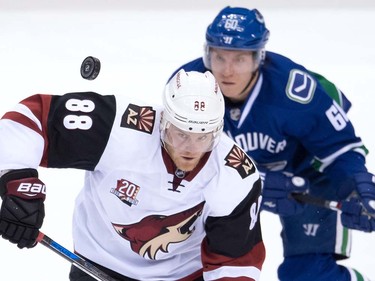 Arizona Coyotes' Jamie McGinn, front, and Vancouver Canucks' Markus Granlund, of Finland, watch the puck during the first period of a pre-season NHL hockey game in Vancouver, B.C., on Monday October 3, 2016.
