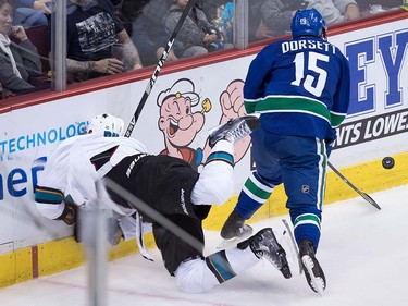 San Jose Sharks' Brenden Dillon, left, crashes into the boards after being hit by Vancouver Canucks' Derek Dorsett during the third period of a pre-season NHL hockey game in Vancouver, B.C., on Sunday October 2, 2016.