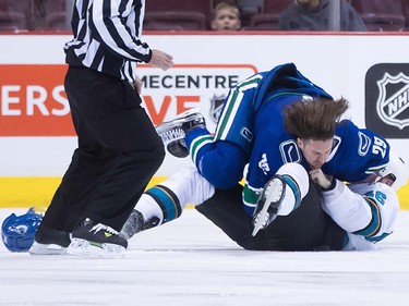 Vancouver Canucks' Andrey Pedan, top, of Lithuania, and San Jose Sharks' Dan Kelly fall to the ice while fighting during the first period of a pre-season NHL hockey game in Vancouver, B.C., on Sunday October 2, 2016.