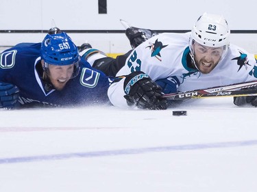 Vancouver Canucks' Alex Biega, left, and San Jose Sharks' Barclay Goodrow dives after the puck during the first period of a pre-season NHL hockey game in Vancouver, B.C., on Sunday October 2, 2016.