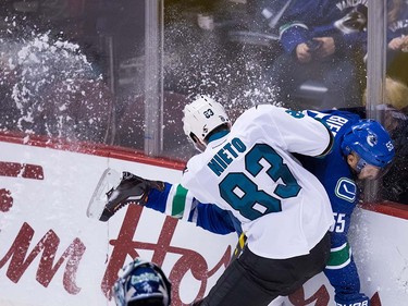San Jose Sharks' Matt Nieto (83) checks Vancouver Canucks' Alex Biega during the third period of a pre-season NHL hockey game in Vancouver, B.C., on Sunday October 2, 2016.