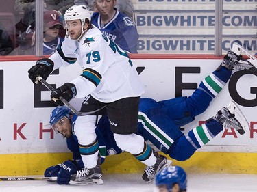 Vancouver Canucks' Chris Tanev, back, fall to the ice behind San Jose Sharks' Alex Gallant during the third period of a pre-season NHL hockey game in Vancouver, B.C., on Sunday October 2, 2016.