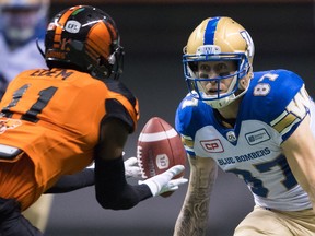 B.C. Lions' Mike Edem, left, intercepts the ball after Winnipeg Blue Bombers' Rory Kohlert failed to make the catch during the first half of Friday's game at B.C. Place.