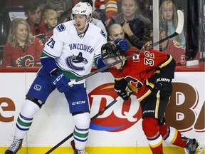 Vancouver Canucks' Andrey Pedan, left, grabs Calgary Flames' Paul Byron during NHL pre-season hockey action in Calgary, Friday, Sept. 25, 2015.