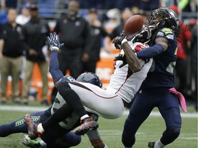 Seahawks cornerback Richard Sherman, right, and Earl Thomas (obscured) break up a pass intended for Atlanta Falcons wide-receiver Julio Jones (11) in the second half Sunday in Seattle. The Seahawks beat the Falcons 26-24.