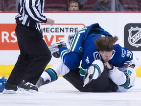 The Canucks' Andrey Pedan and Sharks' Dan Kelly fall to the ice while fighting.