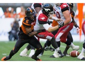 Calgary Stampeders' quarterback Bo Levi Mitchell, right, fumbles the ball as he's hit by B.C. Lions' T.J. Lee during the first half of a CFL football game in Vancouver, B.C., on Saturday June 25, 2016. B.C. recovered the ball on the play.