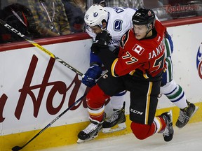 Michael Chaput takes a hit from Calgary Flames' Mark Jankowski while playing for the Canucks during preseason.