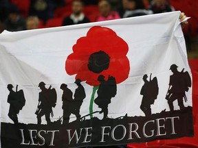 A banner showing the silhouette of troops and a large red poppy with the words &#039;Lest We Forget&#039; is held up by a fan prior to the start of the World Cup 2018 Group F qualification soccer match between England and Scotland at Wembley stadium in London, Friday, Nov. 11, 2016. The game take place on Armistice Day, Nov. 11, when poppies are traditional worn in memory of those who gave their lives in the service of their country in past and present conflicts. (AP Photo/Frank Augstein)